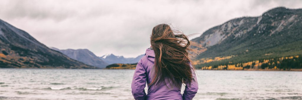 a little girl standing next to a body of water